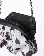 Bolso estampado efecto vaquita con marco rígido y cadena metálica